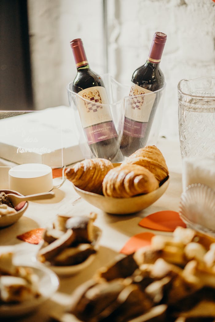 Charming arrangement of wine bottles with pastries and snacks, perfect for romantic gatherings or events.