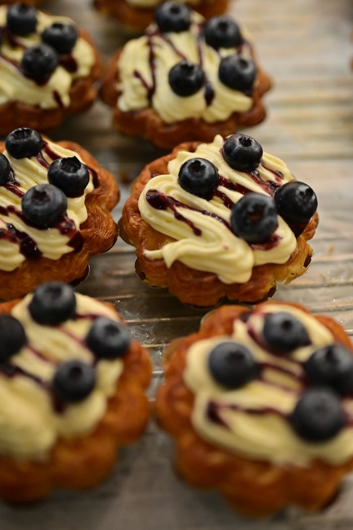 Delicious pastries topped with fresh blueberries and cream on a baking tray.