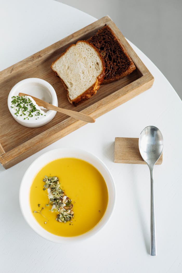 Delicious pumpkin soup served with fresh bread and a creamy dip, perfect for gourmet dining.